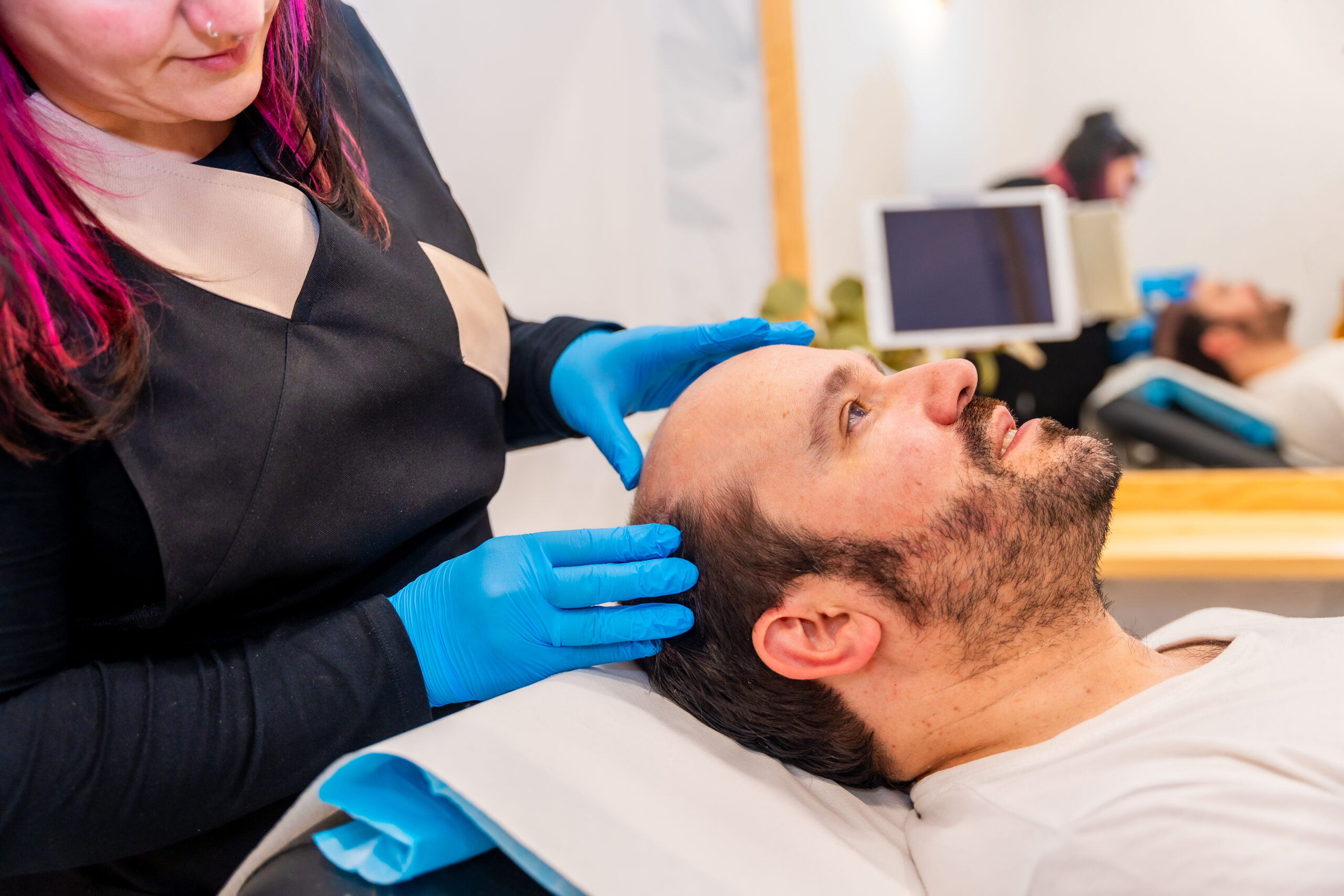 Dermatologist inspecting the bald man's head before a hair treatment Dermatologist inspecting the bald man's head before a hair treatment